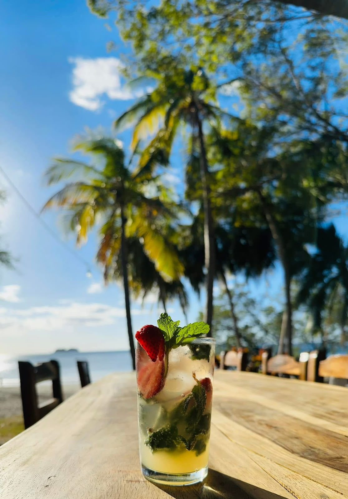 Mojito de fresa sobre una mesa con vista a la playa